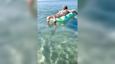 Moglie nuda sul materassino al mare