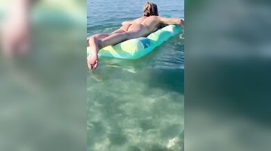 Moglie nuda sul materassino al mare